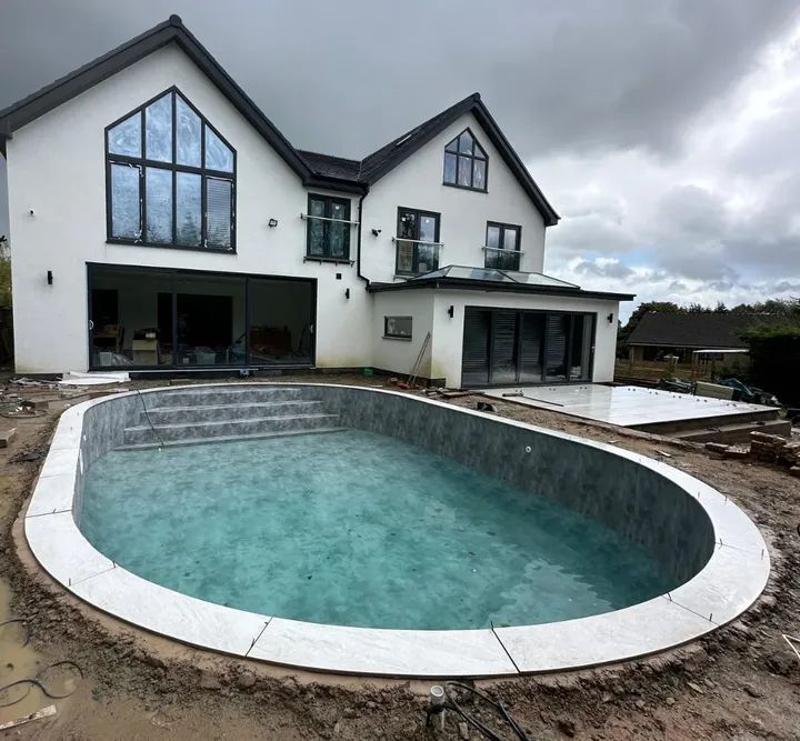 Curved bullnose stone coping running around a pool in front of a house
