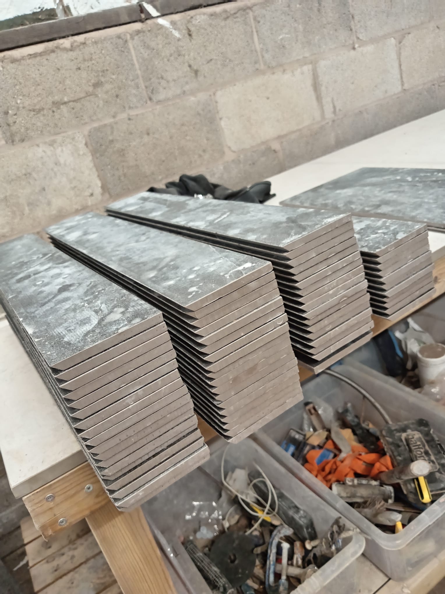 Stacks of grey porcelain tiles with mitred edges ready in the workshop