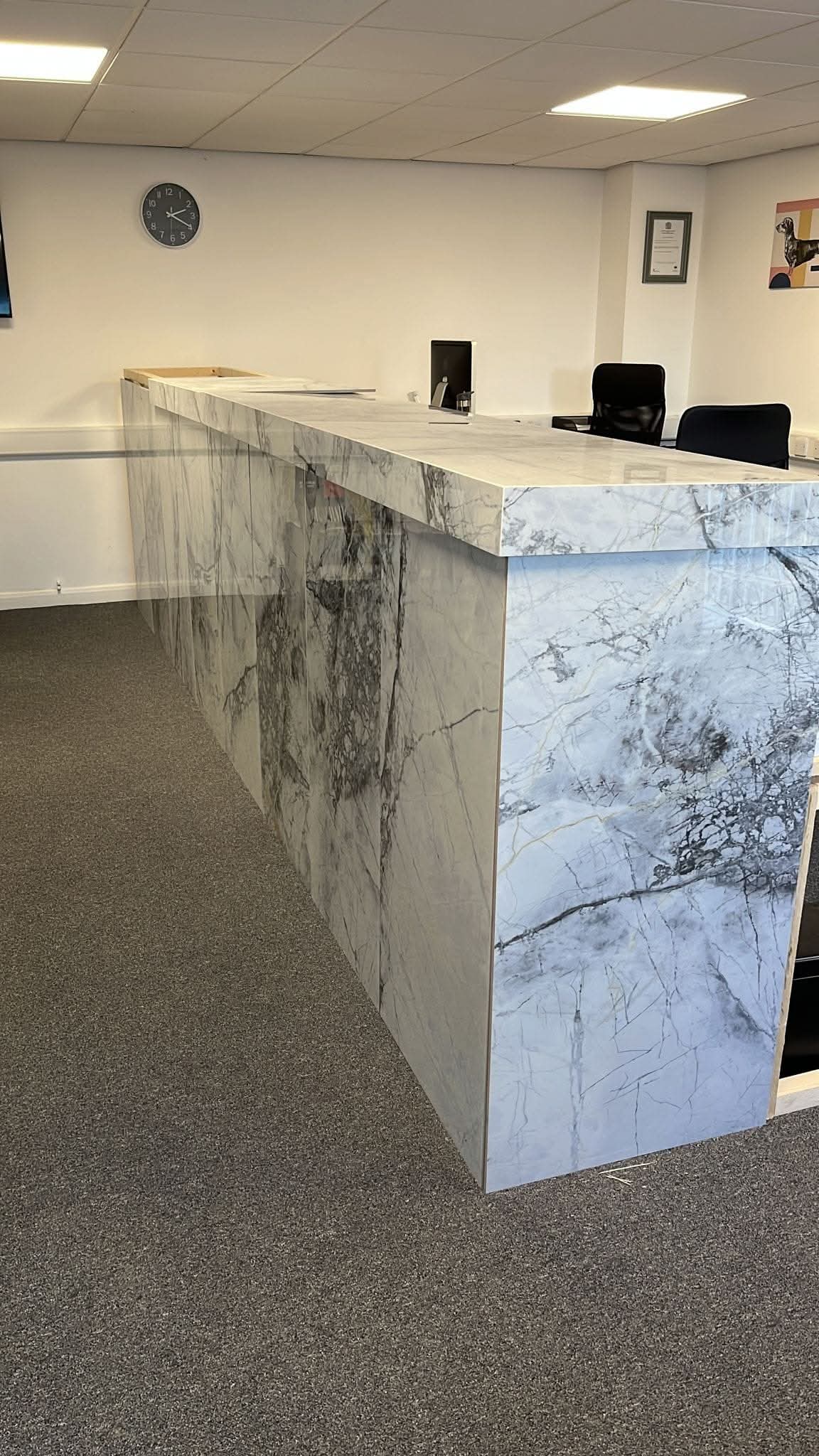 Large-format marble-effect porcelain reception desk with waterfall edges