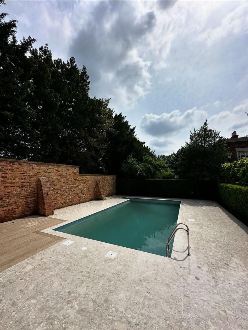 Porcelain pool coping run installed on-site in a walled garden