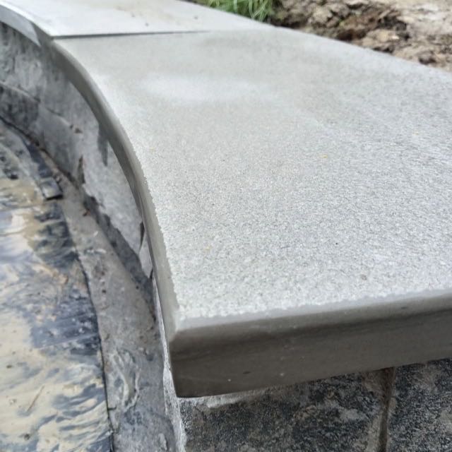 Curved 30mm limestone copings with a pencil-round edge