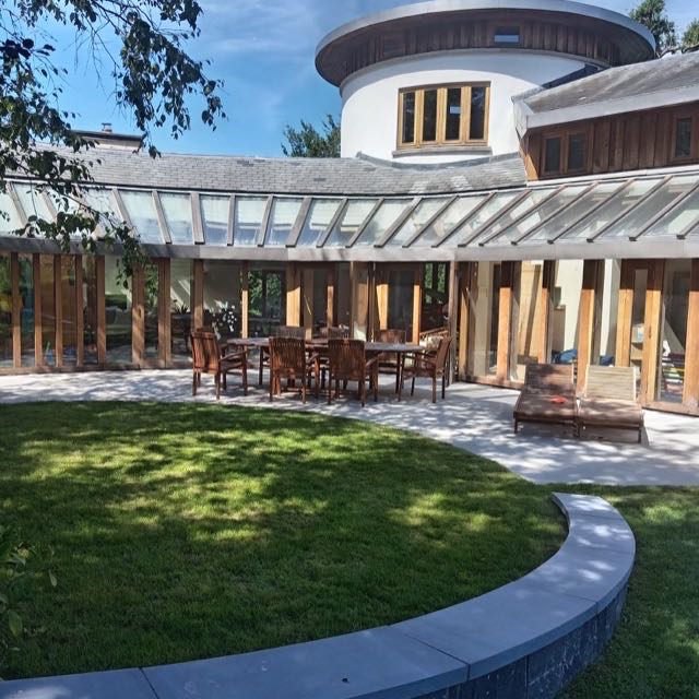 Curved stone patio dining terrace beside a circular lawn