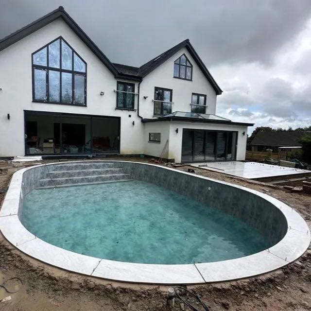 Curved bullnose stone pool coping in front of a house