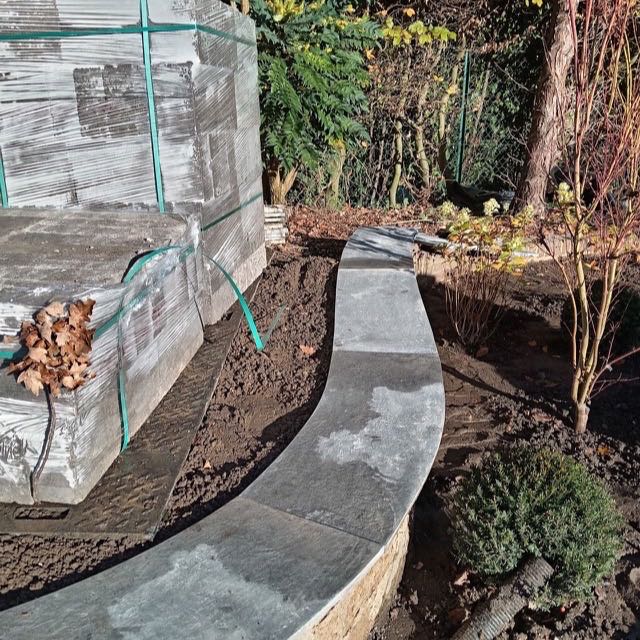 Curved stone coping being installed on a wall
