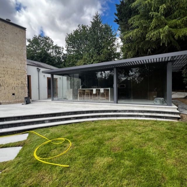 Glass garden pavilion and outdoor kitchen on a stone terrace