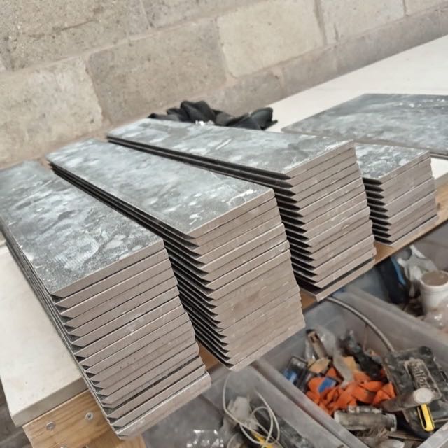 Stacks of grey porcelain tiles with mitred edges ready in the workshop