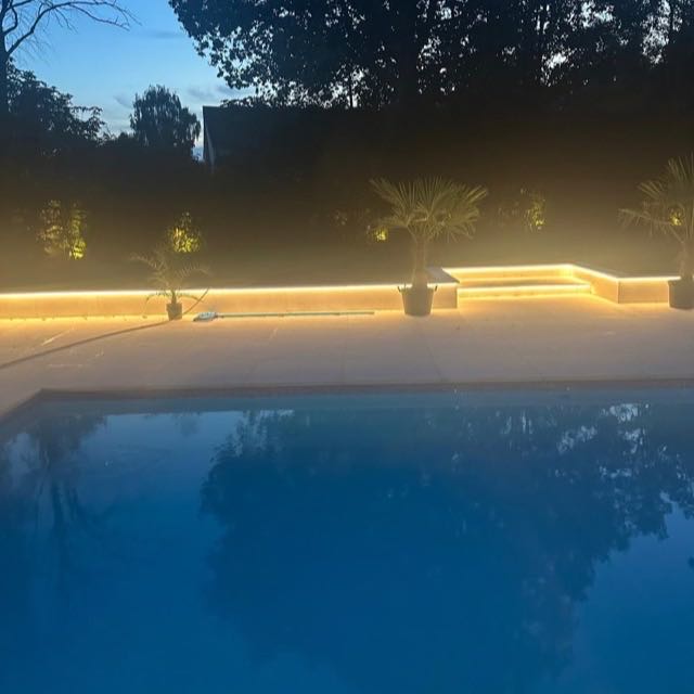 LED-lit pool terrace with stone seating at dusk