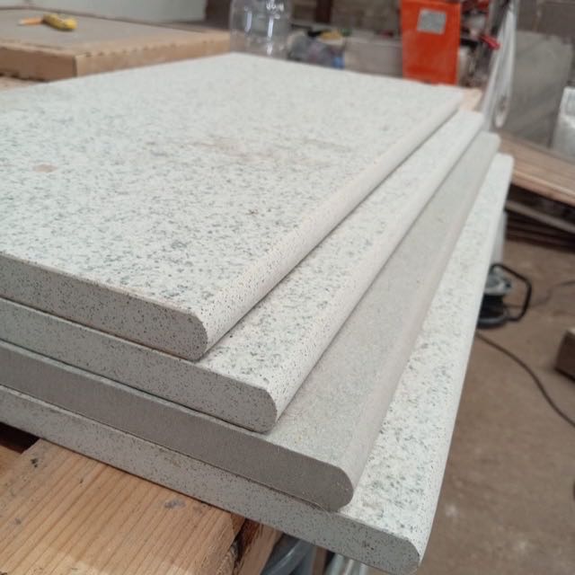 Stack of light grey slabs with full bullnose edges