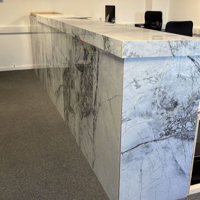 Marble-effect porcelain reception desk with waterfall edges