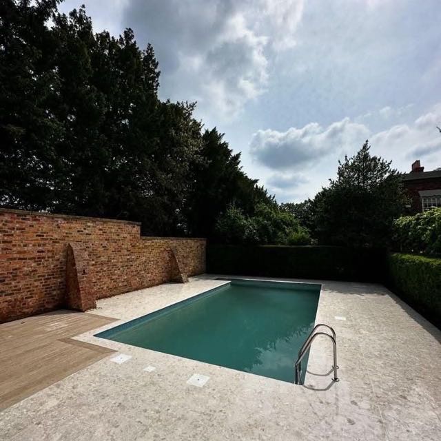 Outdoor pool with stone coping in a walled garden