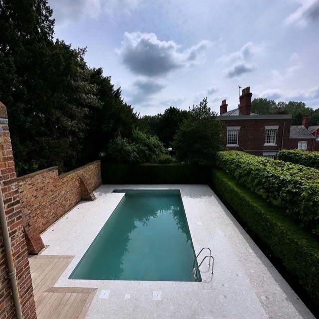 Stone coping running around a pool in a walled garden