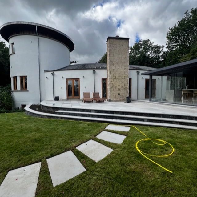 Rear stone terrace with a stone chimney and new lawn at a round tower house