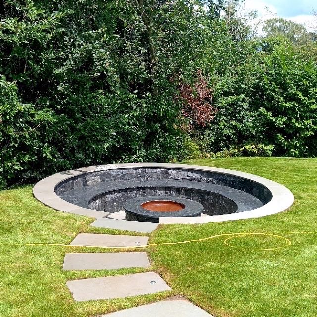 Sunken fire pit with a copper bowl and stepping stone path