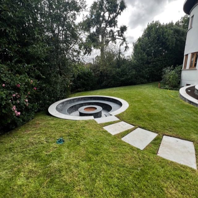 Sunken fire pit in a lawn with stepping stones at a round tower house