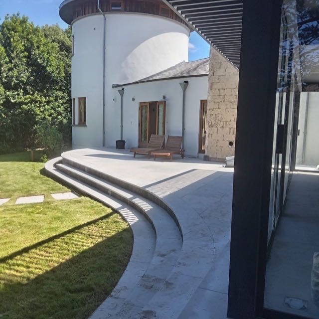 Sweeping curved stone steps to a terrace at a round tower house