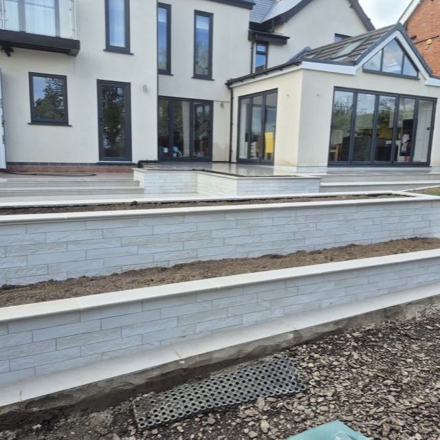 Tiered porcelain-clad retaining walls in a landscaped garden