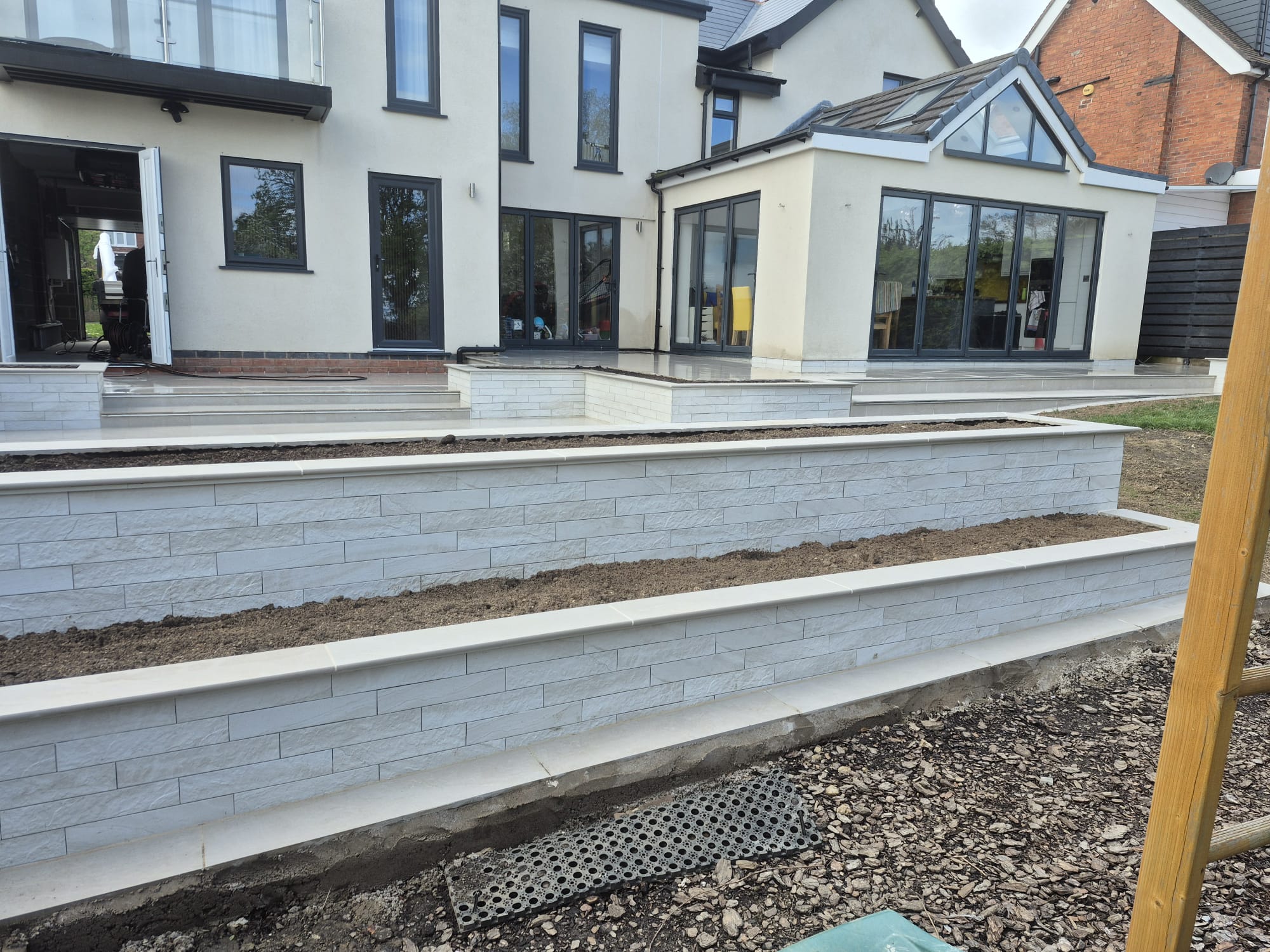 Tiered porcelain-clad retaining walls in a landscaped garden